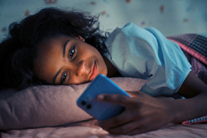 Niña usando un teléfono móvil por la noche